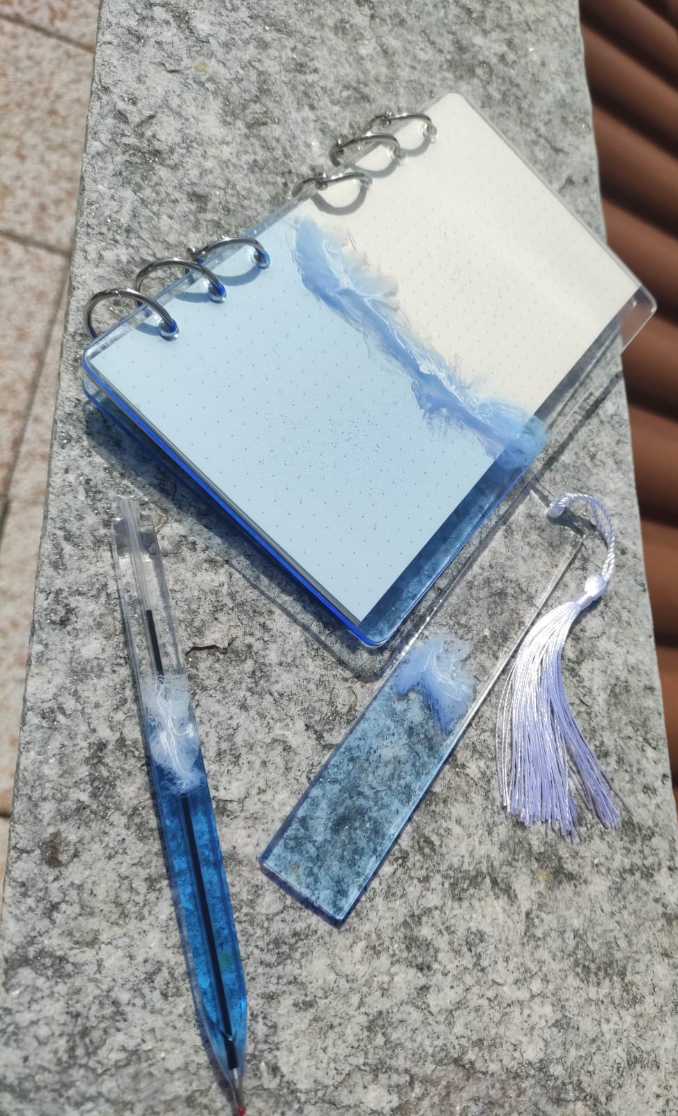 Set da cancelleria in resina artigianale a tema mare con effetto onde blu e schiuma bianca, composto da un taccuino con anelli metallici, una penna e un segnalibro 