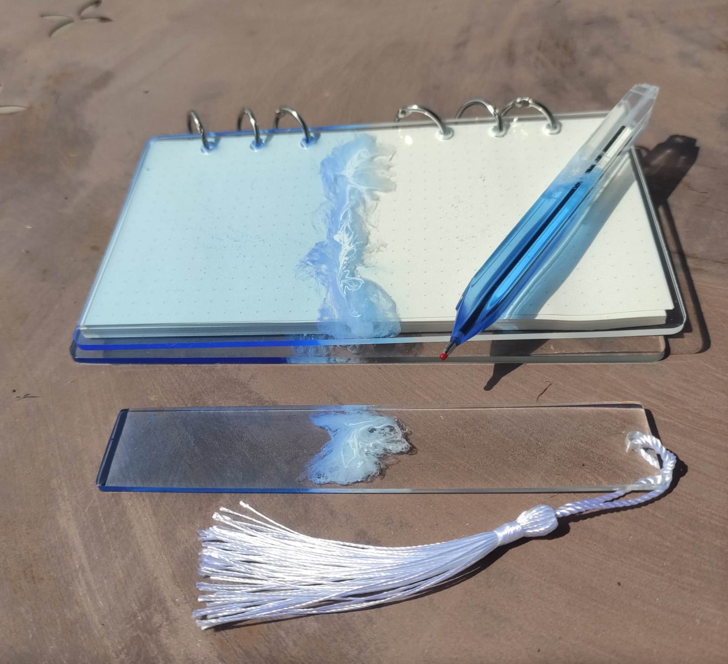 Set da cancelleria in resina artigianale a tema mare con effetto onde blu e schiuma bianca, composto da un taccuino con anelli metallici, una penna e un segnalibro 