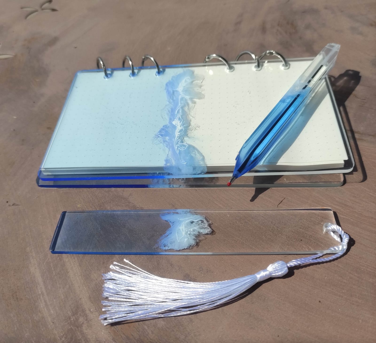 Set da cancelleria in resina artigianale a tema mare con effetto onde blu e schiuma bianca, composto da un taccuino con anelli metallici, una penna e un segnalibro 