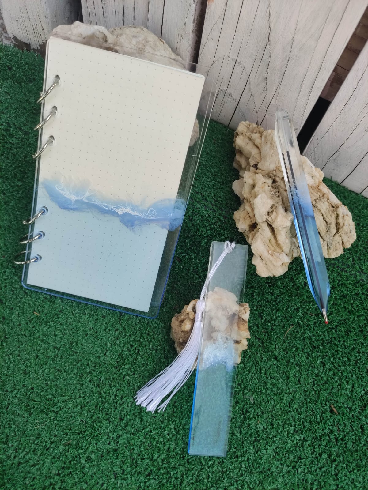 Set da cancelleria in resina artigianale a tema mare con effetto onde blu e schiuma bianca, composto da un taccuino con anelli metallici, una penna e un segnalibro 
